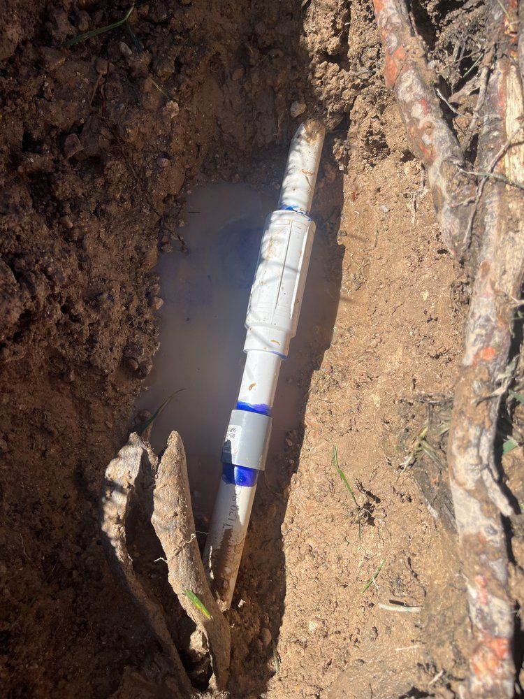 PVC pipe repair in a dirt trench, with water present.