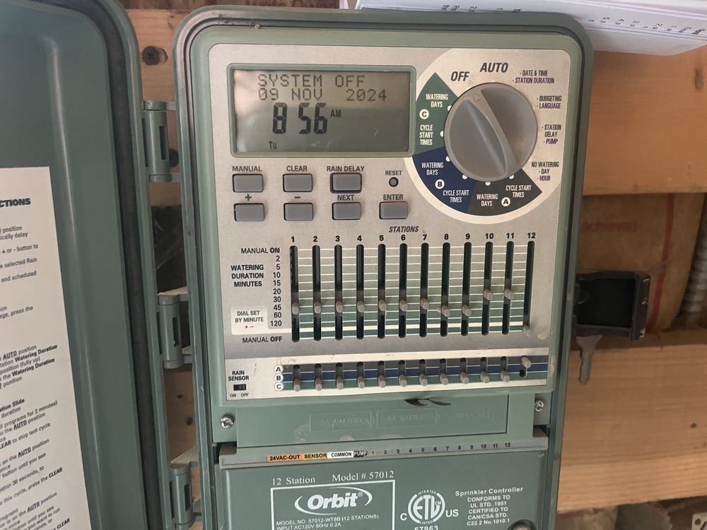 Green Orbit sprinkler system control panel with digital display and manual sliders.