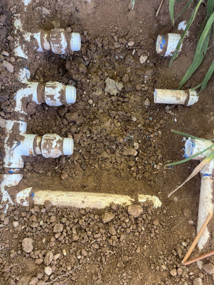 White PVC irrigation pipes buried in soil.
