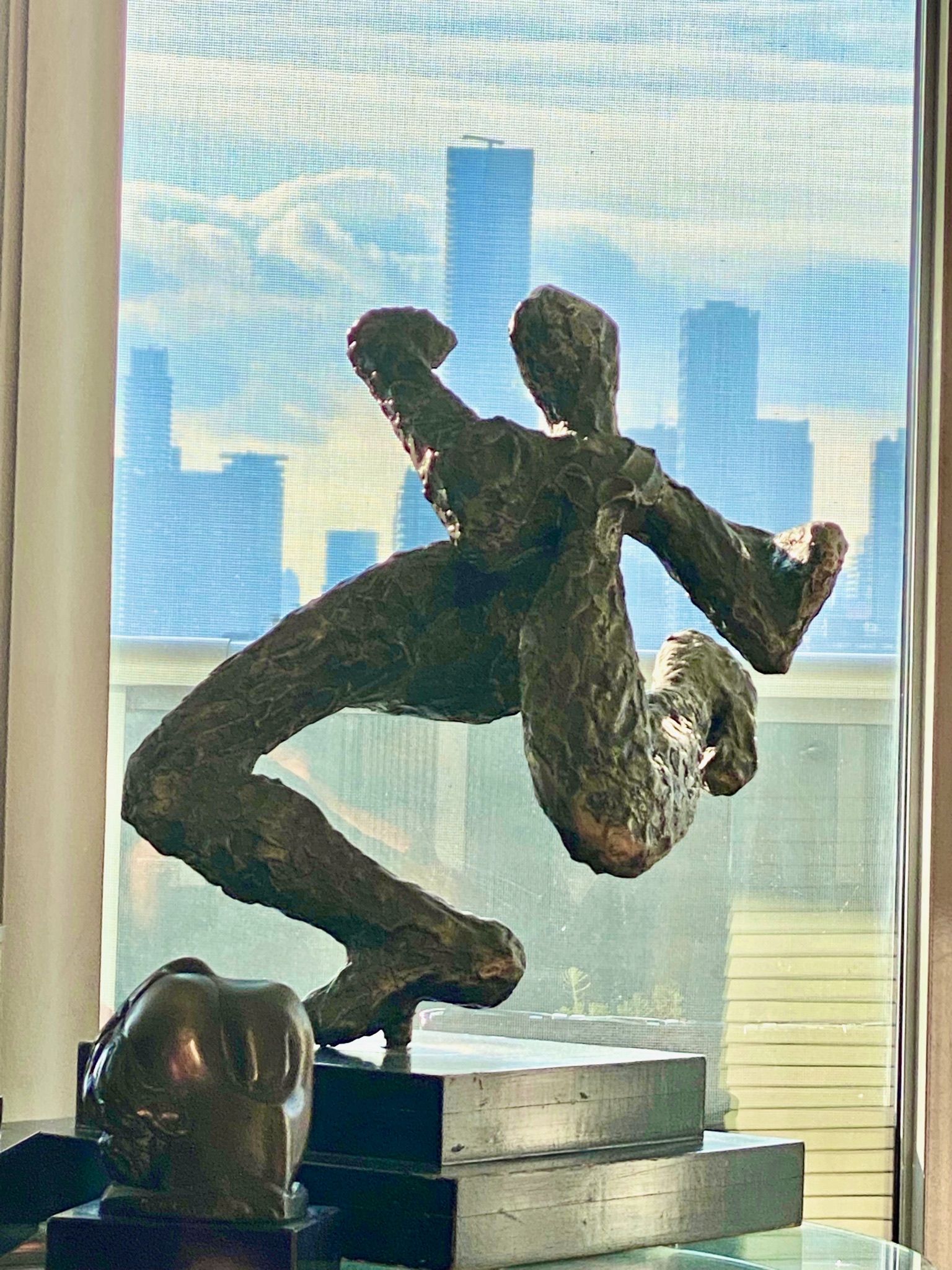 A statue of a person doing a handstand in front of a window.