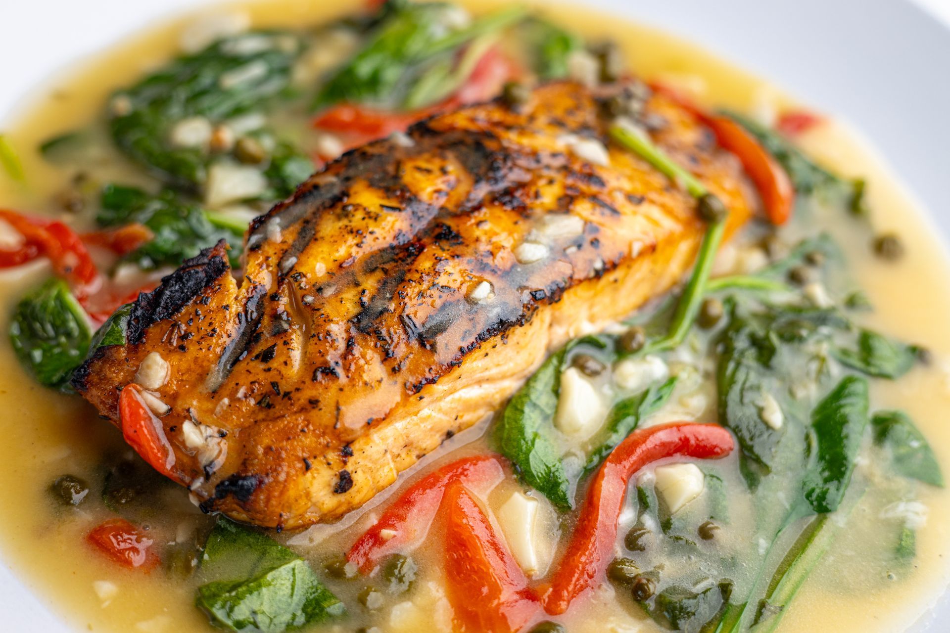 A close up of a plate of food with fish and vegetables on a table.