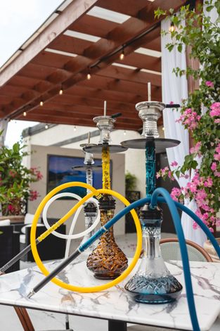 Three hookahs are sitting on a table under a pergola.