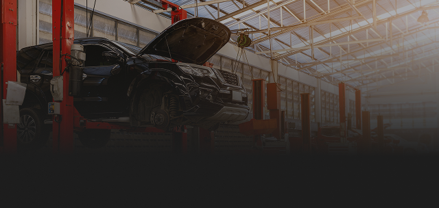 A car being lifted in an auto repair shop with the hood open. | Destiny Vehicle Solutions