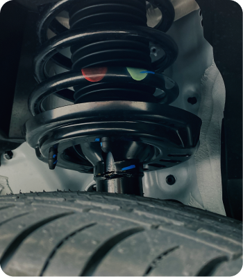 Black car suspension system with a coil spring above a tire. | Destiny Vehicle Solutions