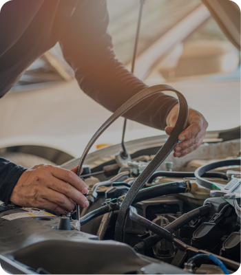 Mechanic holding a serpentine belt near the engine of a car with hood open. | Destiny Vehicle Solutions