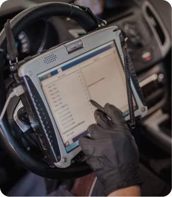 Mechanic using a diagnostic tablet inside a car; wearing black gloves. | Destiny Vehicle Solutions