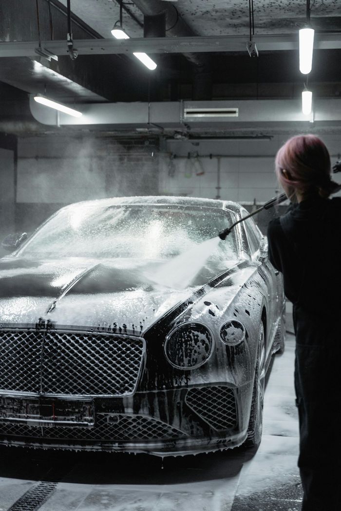 A man is washing a bentley car in a garage
