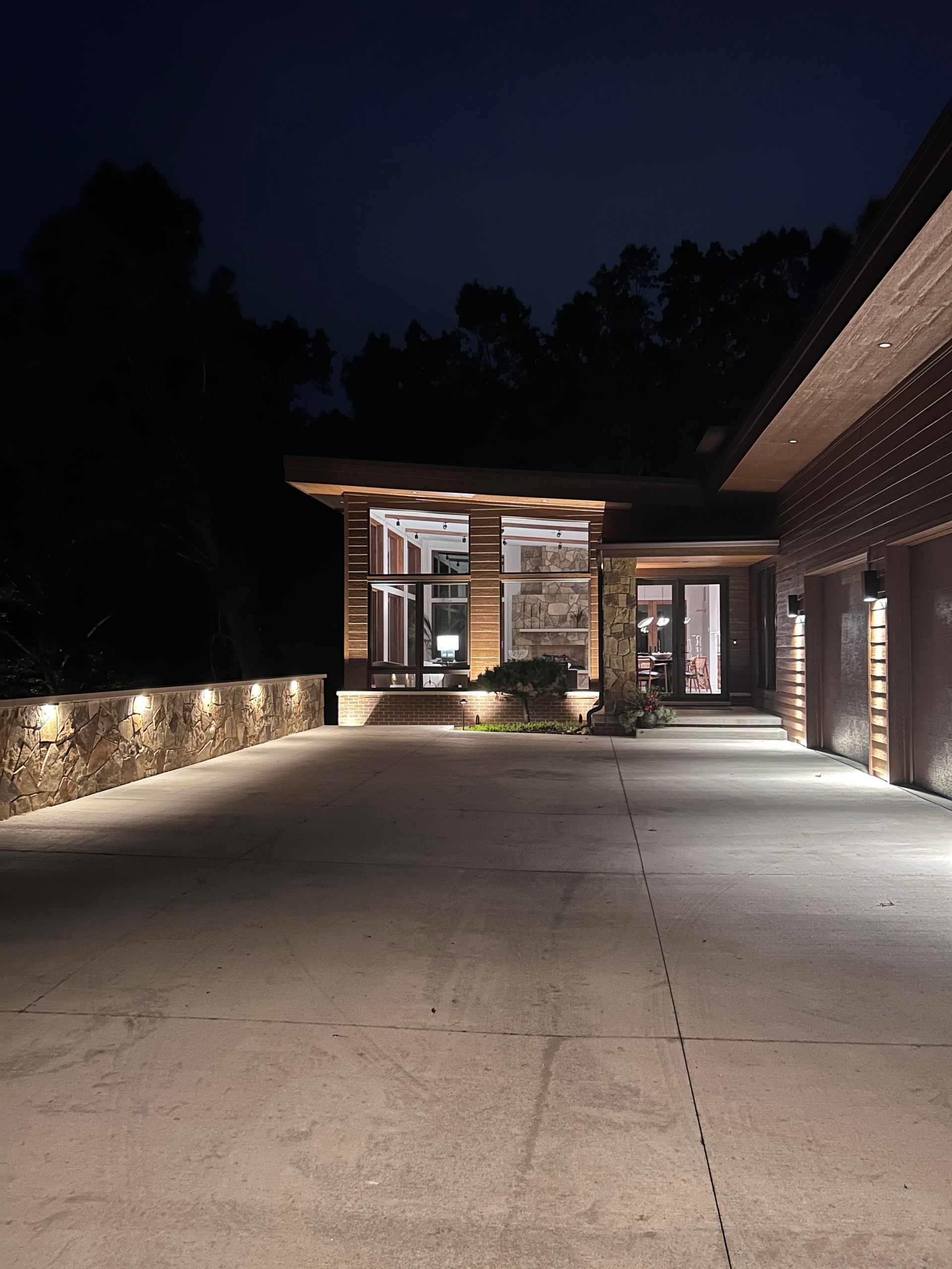 A driveway leading to a house is lit up at night