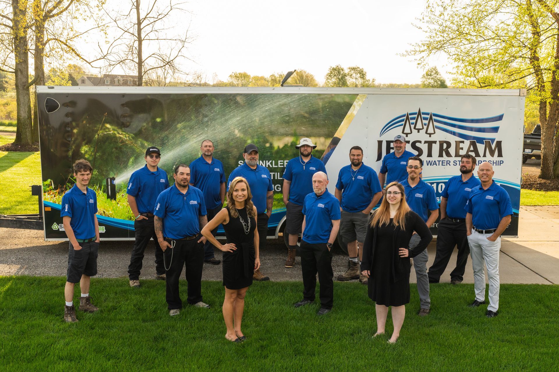 A group of people are posing for a picture in front of a truck.