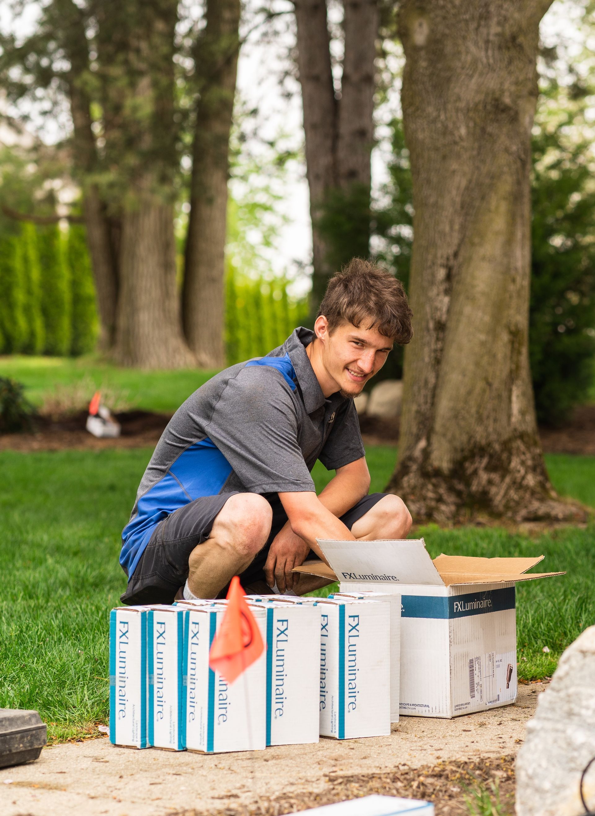 A young man is kneeling down in front of a pile of boxes.
