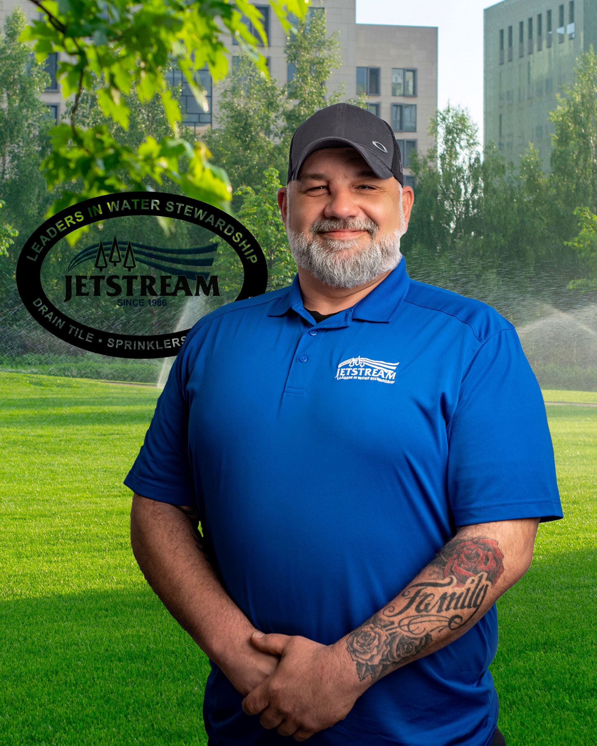 A man in a blue shirt and hat is standing in a grassy field.