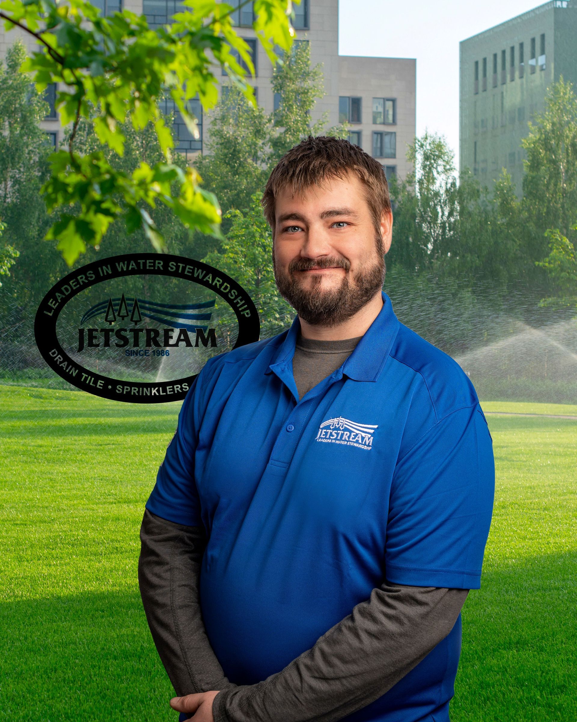 A man in a blue shirt is standing in a grassy field.
