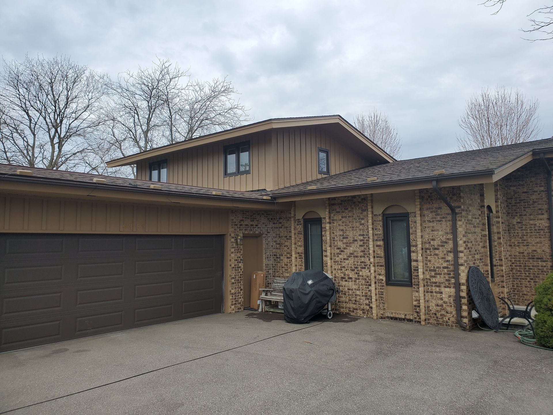 A large house with a garage and a black cover on the driveway.