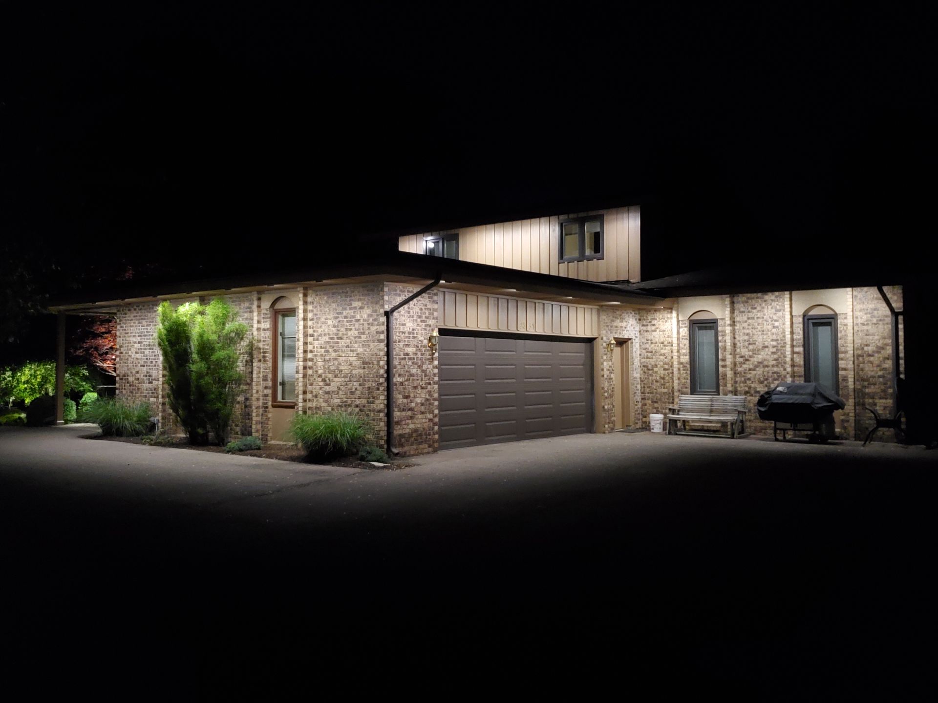 A house with a garage door is lit up at night.