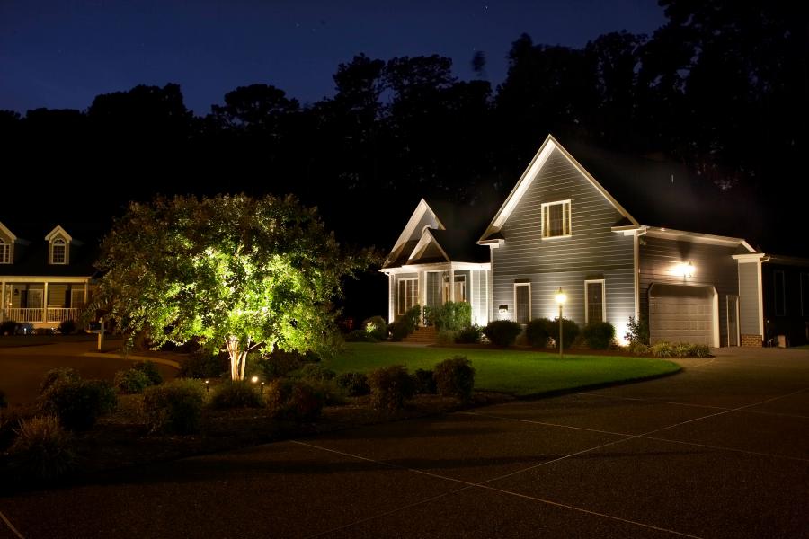 A house is lit up at night with a tree in front of it.