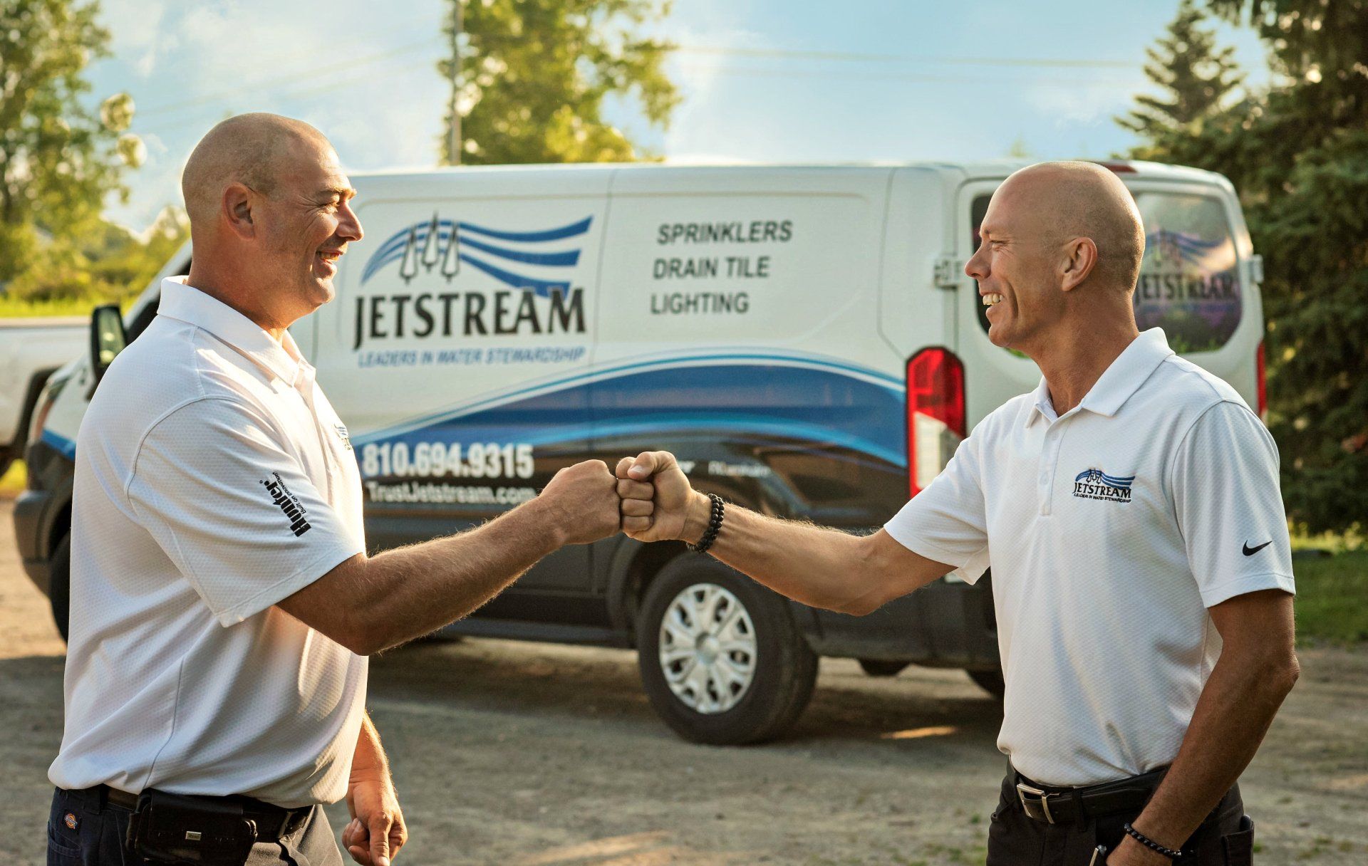 Two men are shaking hands in front of a jetstream van.