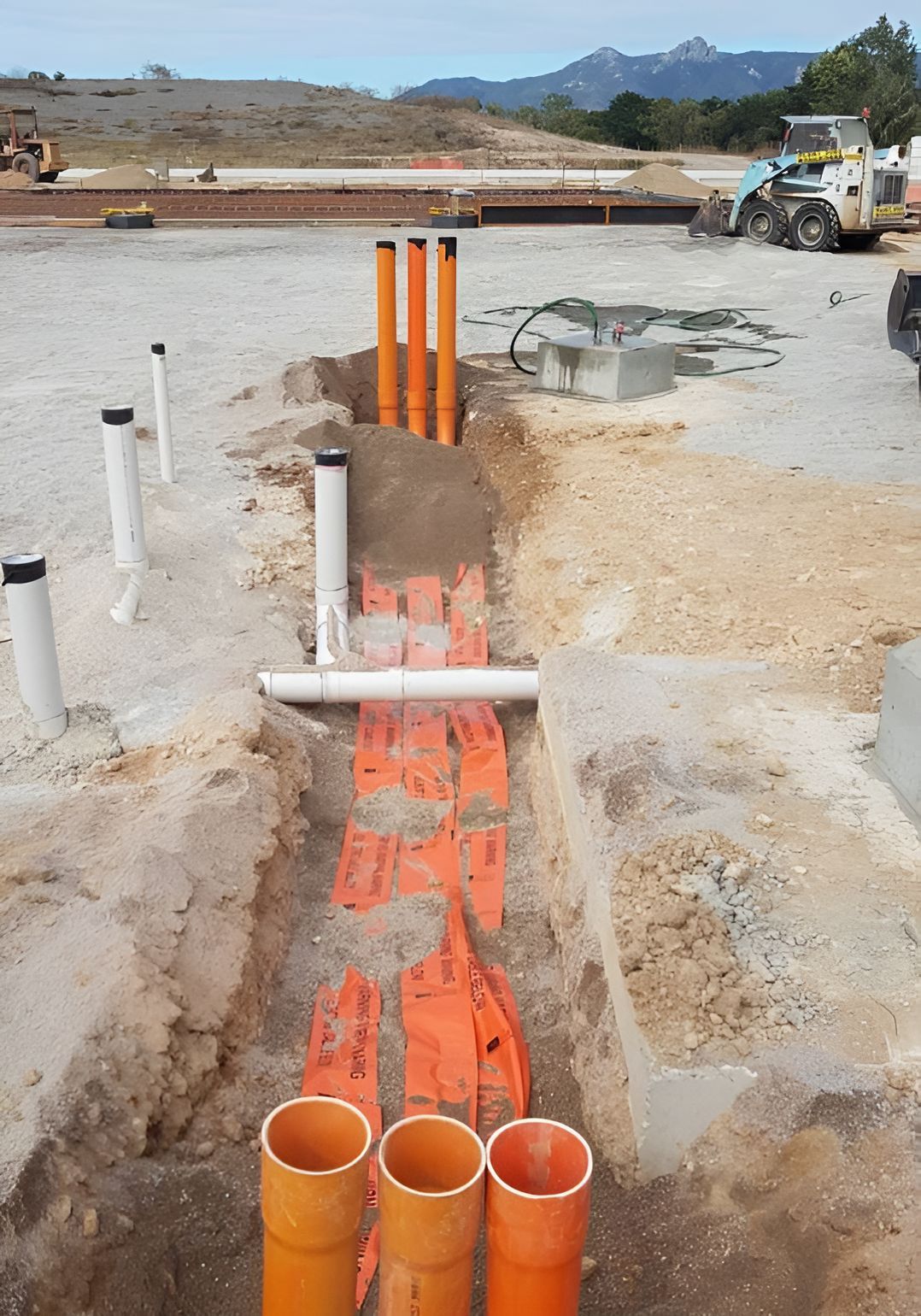 A Bunch Of Pipes Are Laying In The Dirt On A Construction Site — Waltlec Industries In Garbutt, QLD