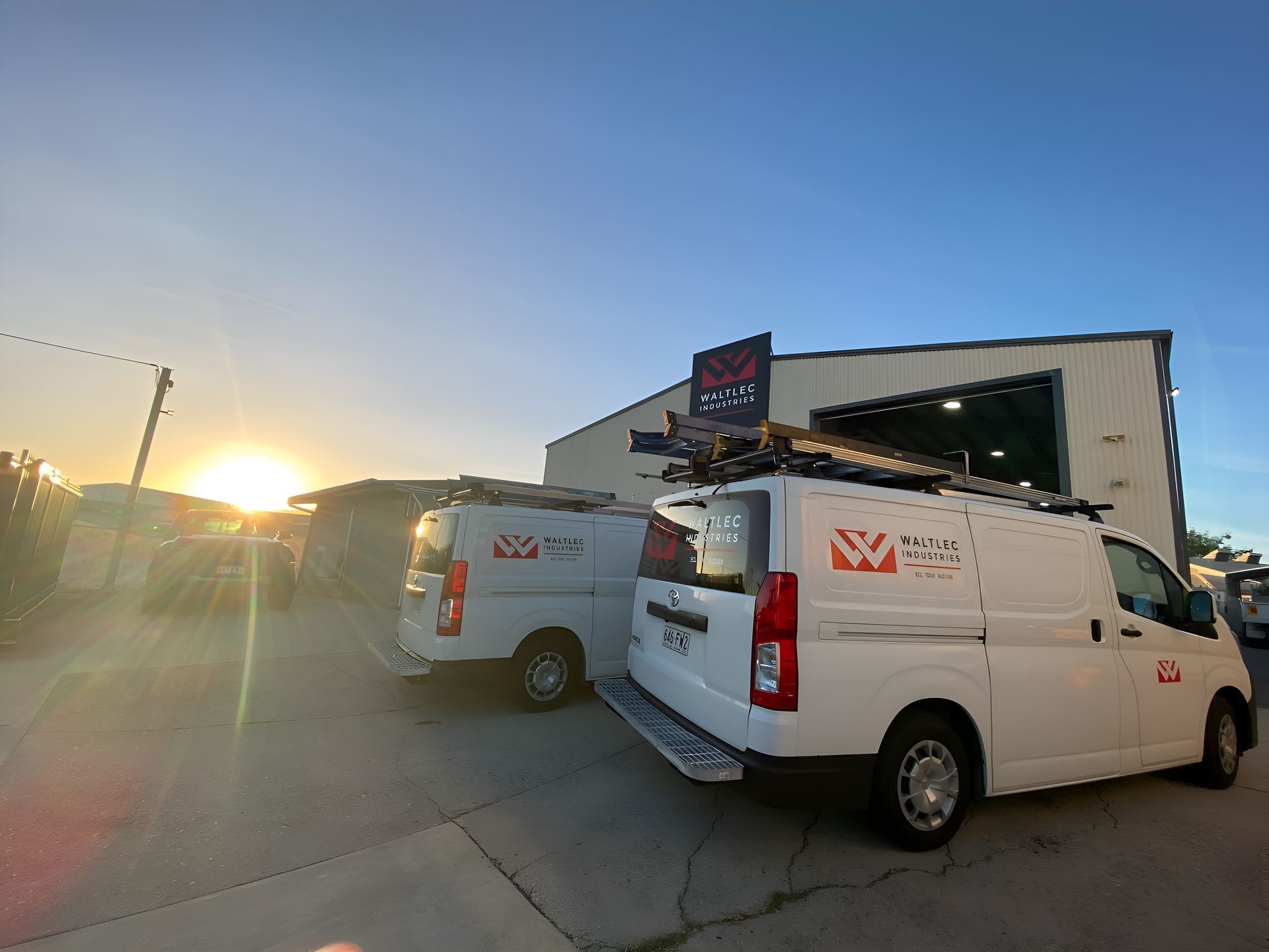 Two White Vans Are Parked In Front Of A Building  — Waltlec Industries In Garbutt, QLD