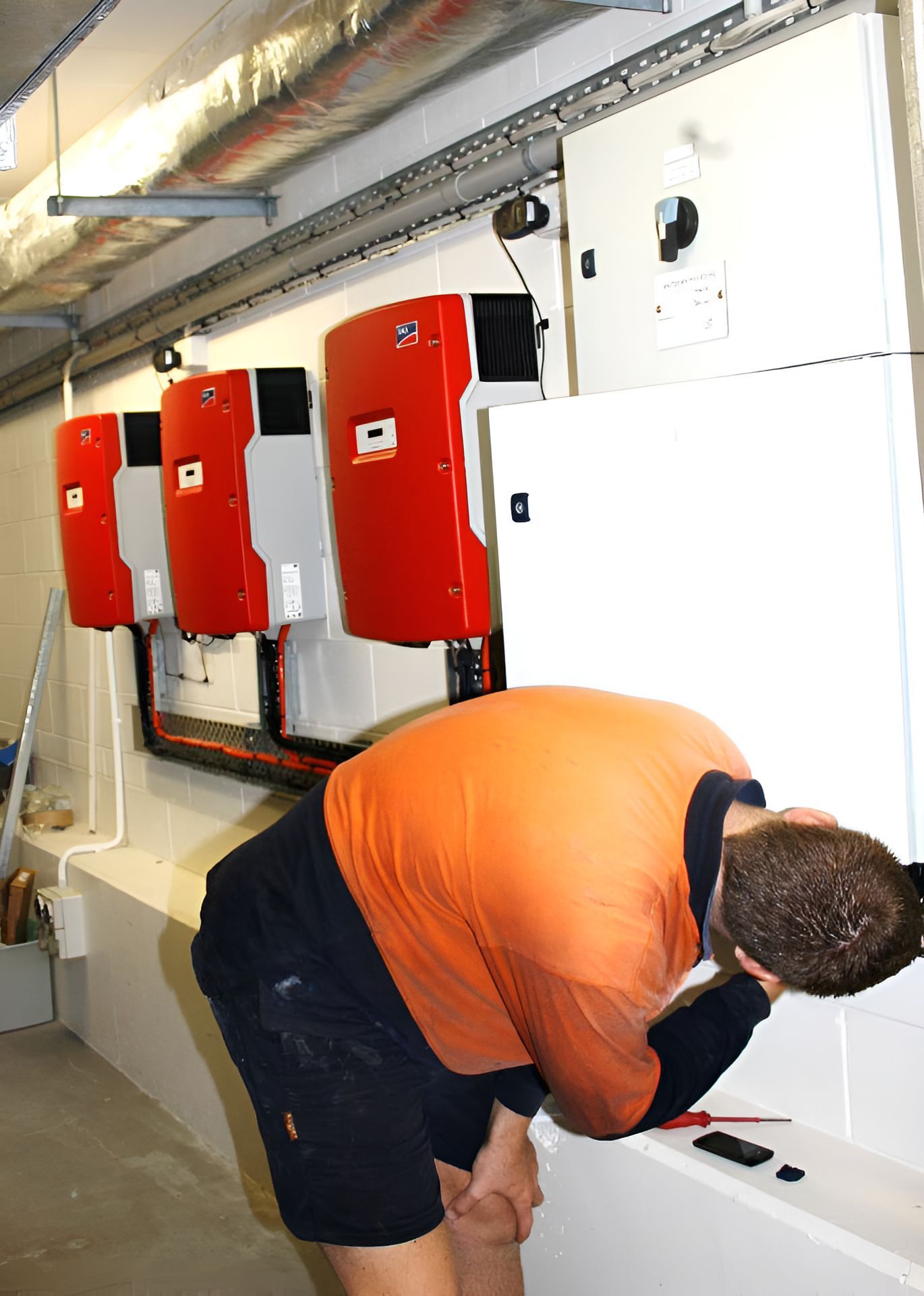 A Man In An Orange Shirt Is Working On A Solar Panel  — Waltlec Industries In Garbutt, QLD