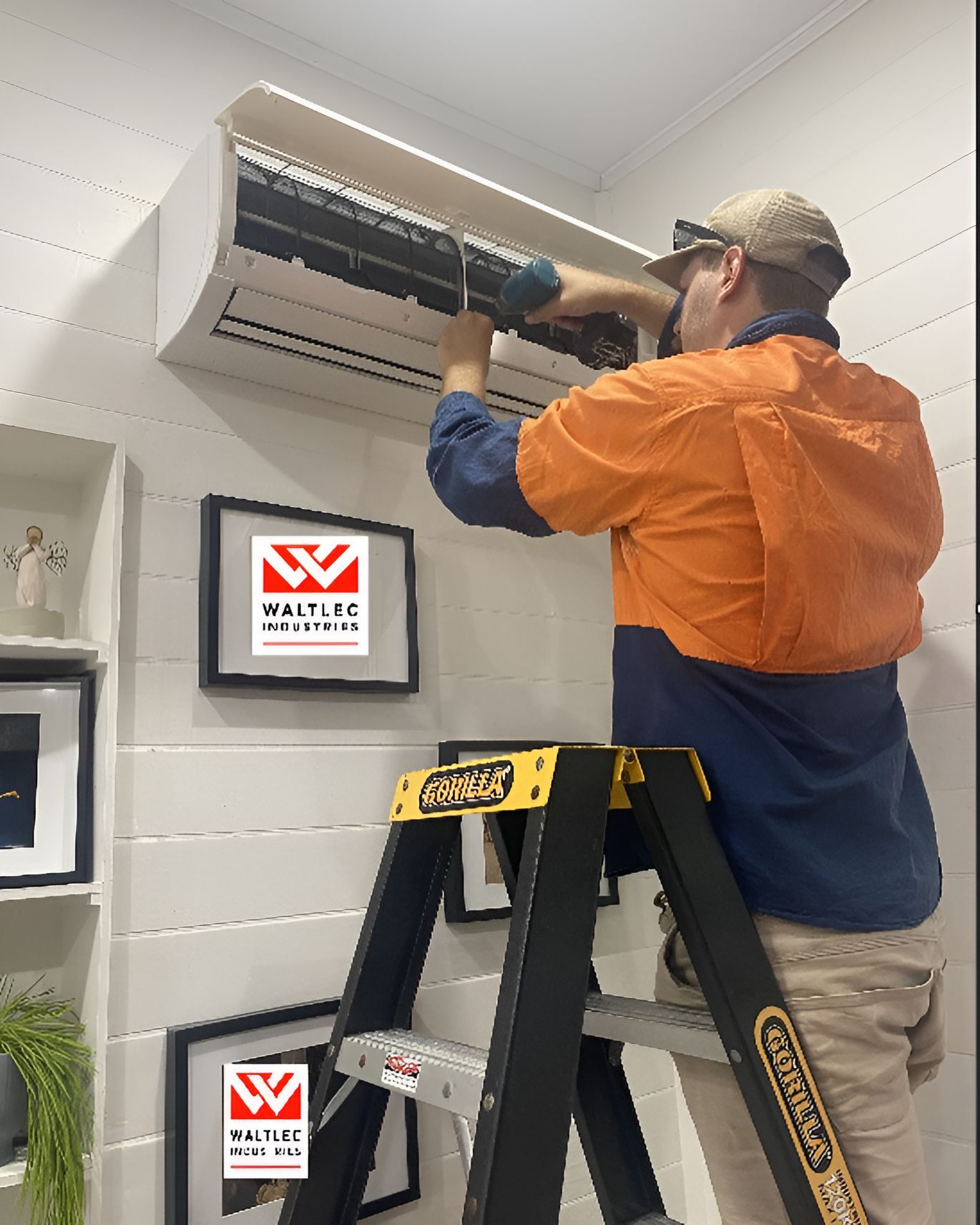A Man Is Standing On A Ladder Fixing An Air Conditioner  — Waltlec Industries In Garbutt, QLD