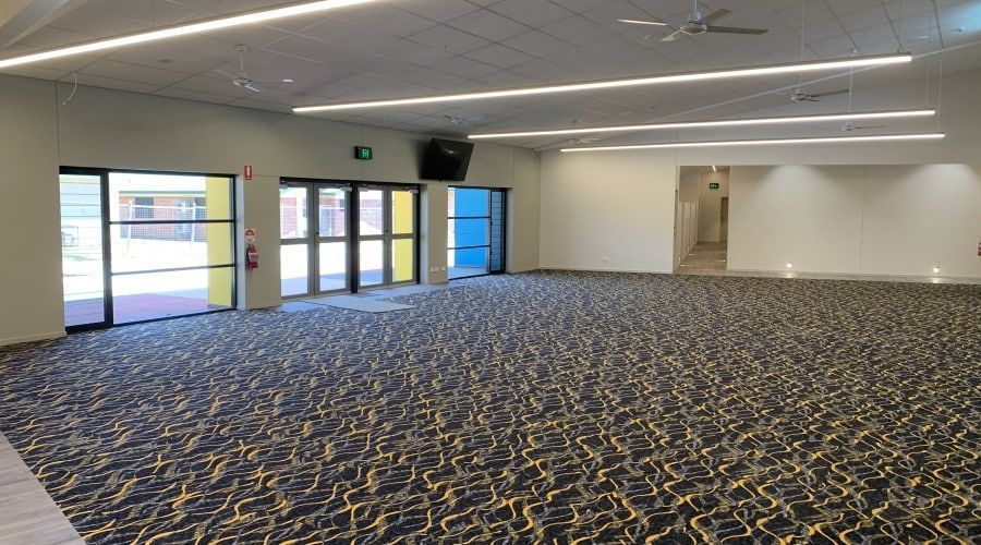 A Large Empty Room with A Blue and Yellow Carpet — Waltlec Industries In Garbutt, QLD
