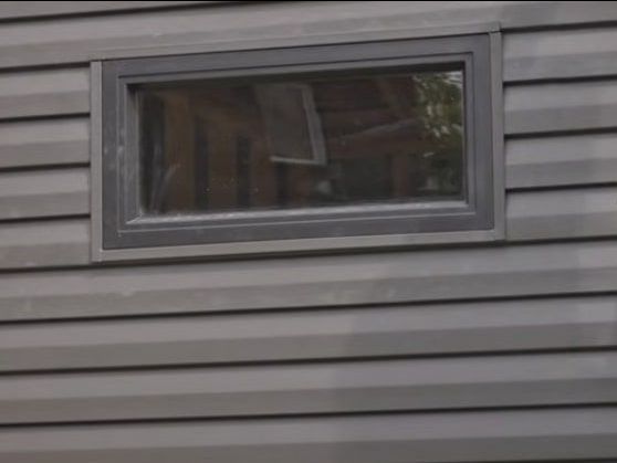 A close up of a gray siding replacement with a window on it.