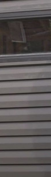 A close up of a gray siding replacement with a window on it.
