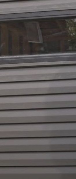 A close up of a gray siding replacement with a window on it.