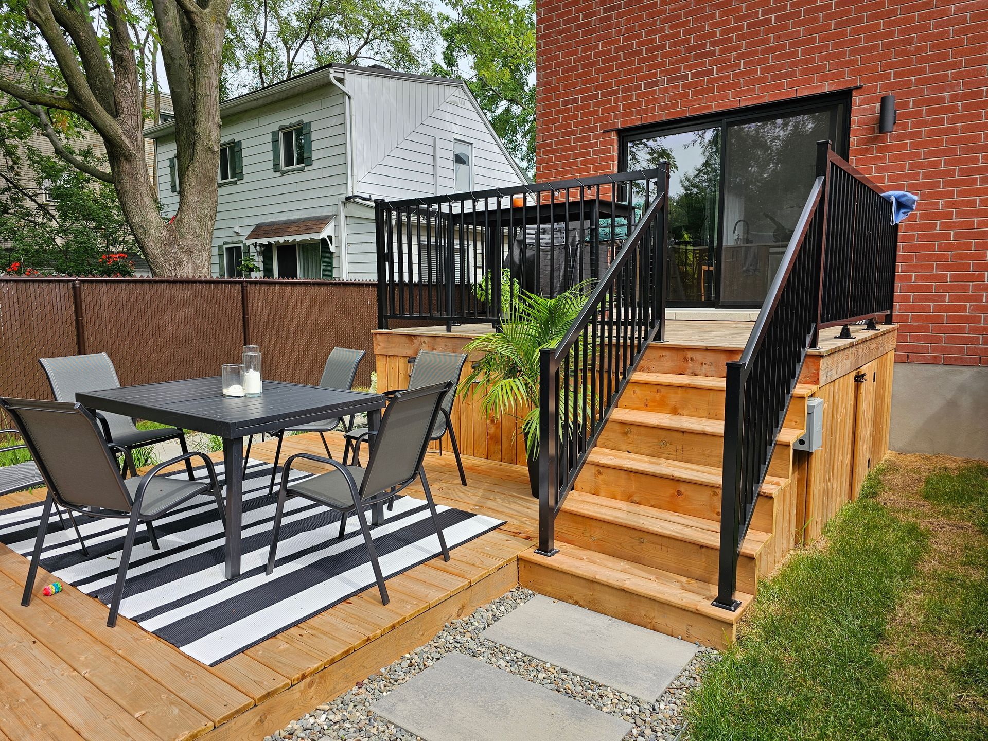 Une terrasse en bois avec une table et des chaises et des escaliers qui y mènent.