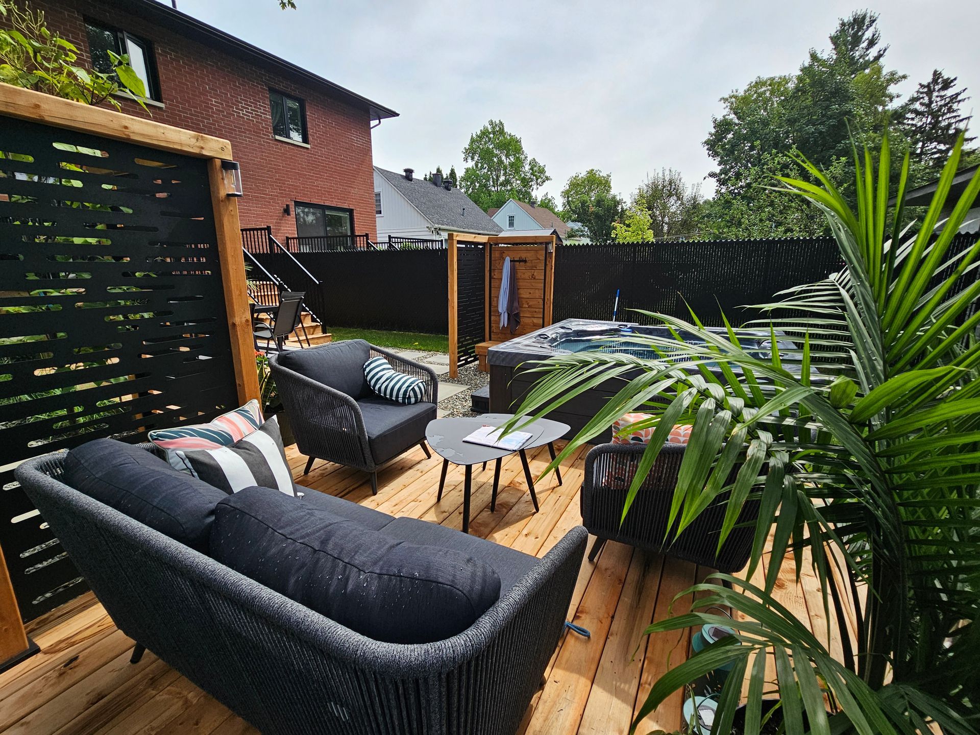 Une terrasse en bois avec un canapé, des chaises et un bain à remous.
