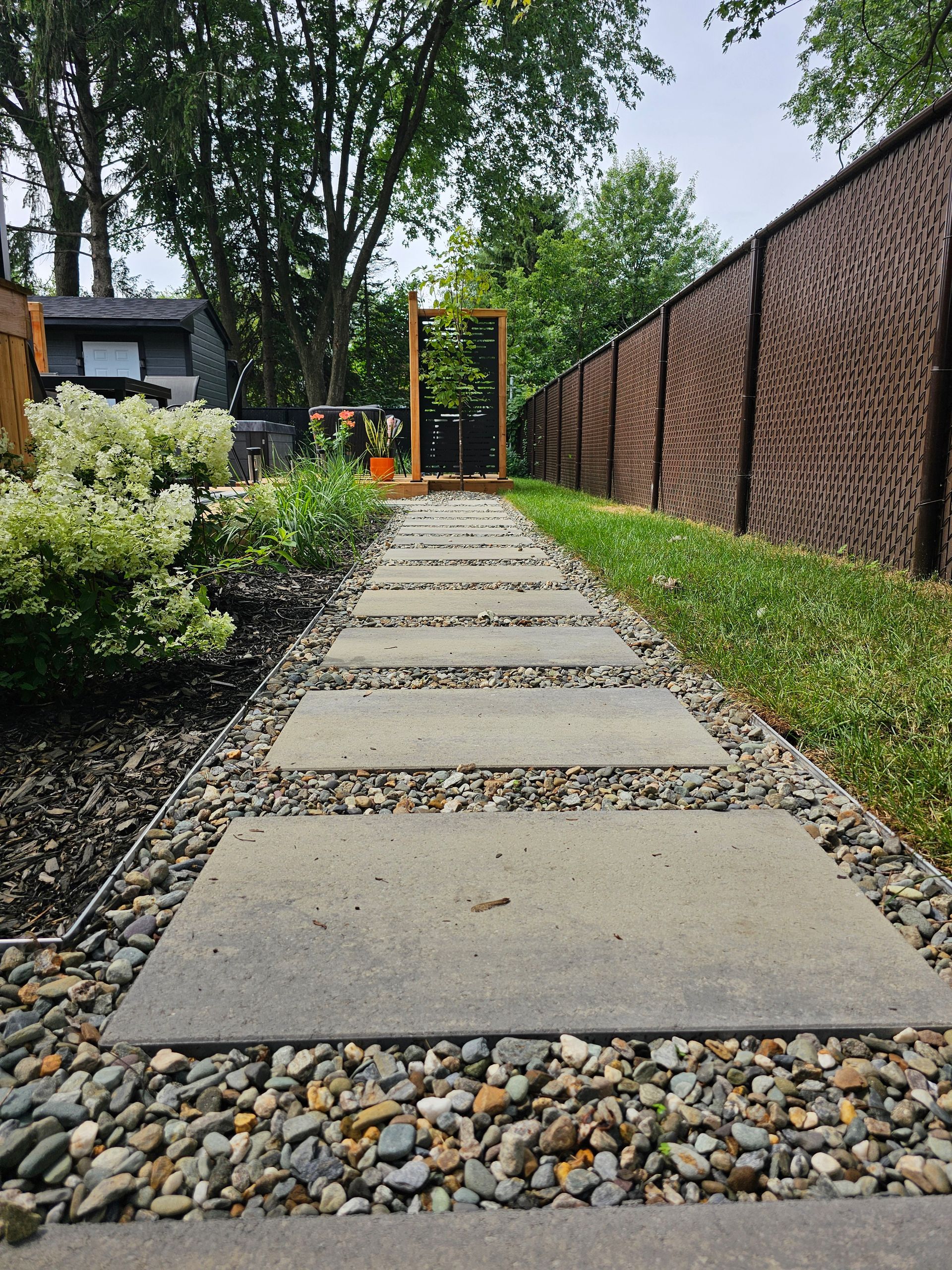 Une allée en pierre menant à une clôture dans une cour arrière.