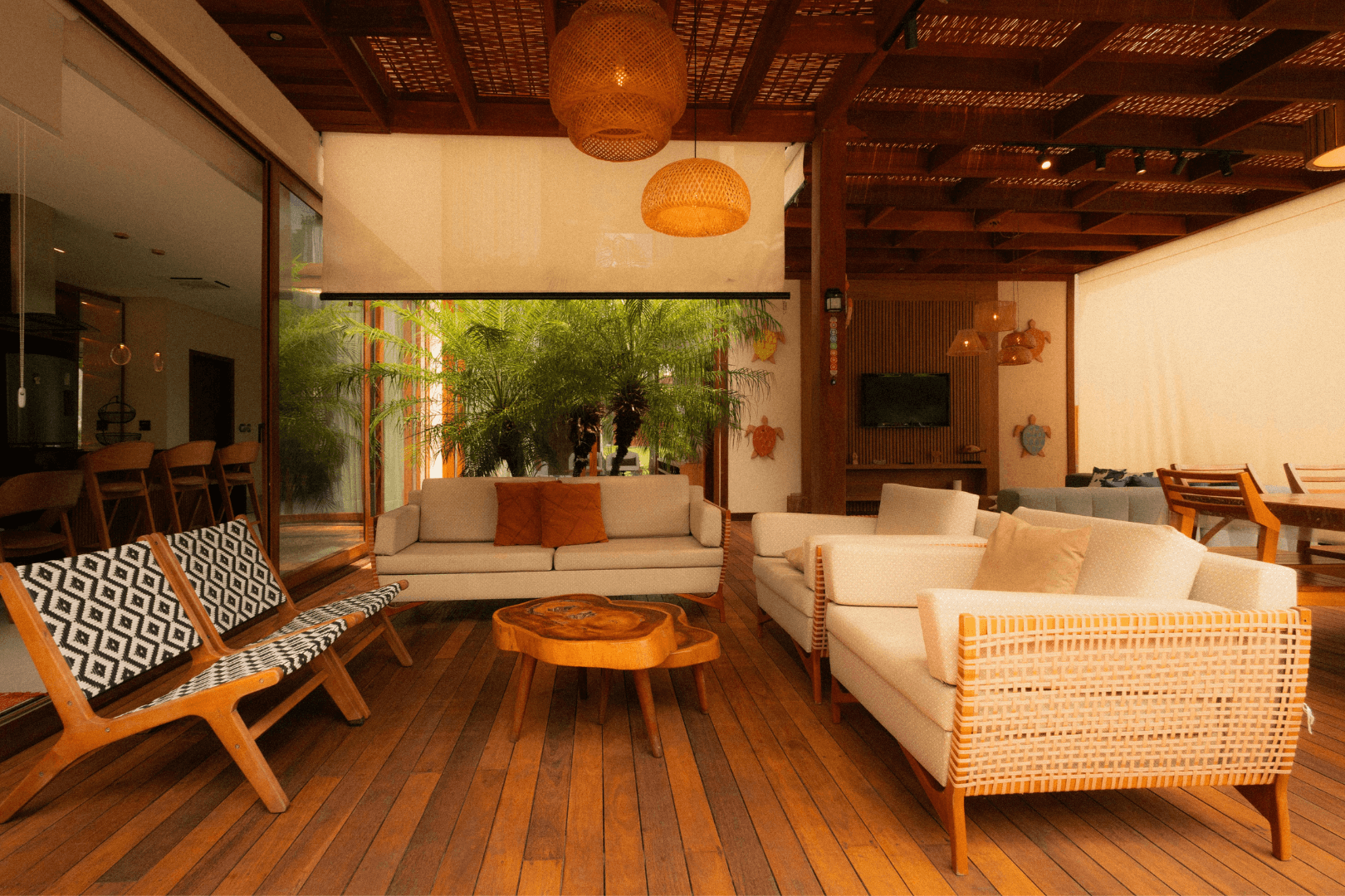 Worker in orange vest rolling black asphalt strip on sandy ground. Concrete border visible.