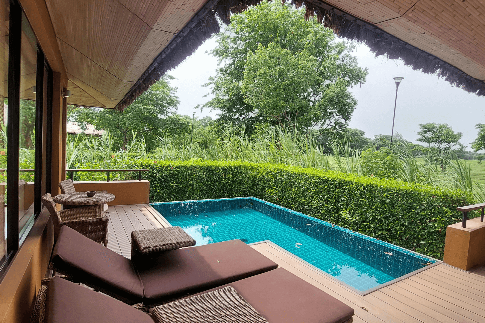 A gloved hand uses a trowel to smooth wet concrete along a brick border outdoors.