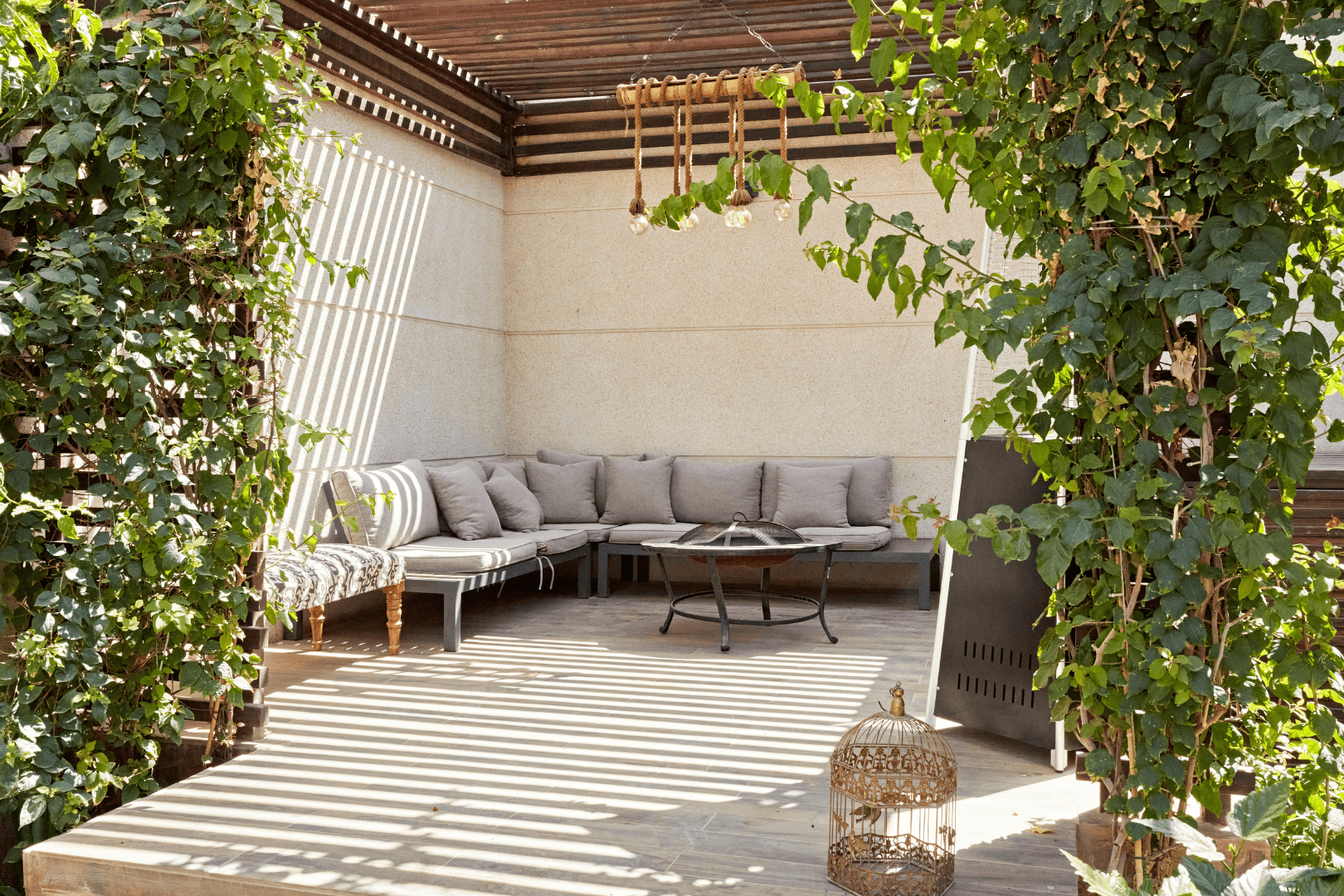 Worker in orange vest rolling black asphalt strip on sandy ground. Concrete border visible.