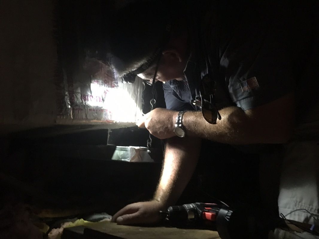 A man is looking under a table with a flashlight.