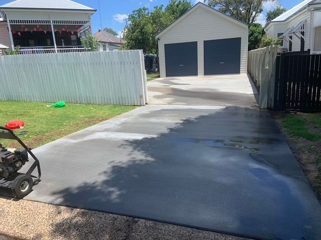 A Concrete Driveway With a Lawn Mower Parked in Front of a House — Pedro's Concreting in Pittsworth, QLD