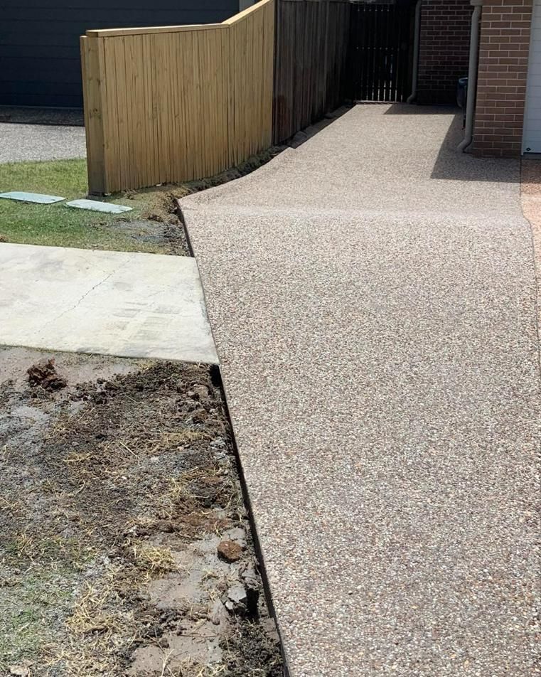 A Concrete Walkway Leading to A House with A Wooden Fence — Pedro's Concreting in Pittsworth, QLD