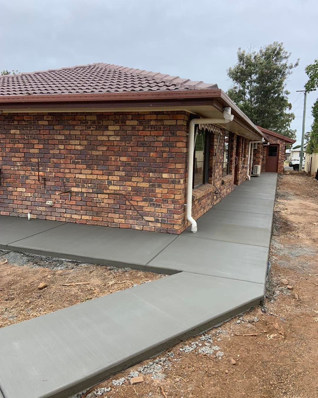 A Brick House With a Concrete Walkway Leading to It — Pedro's Concreting in Pittsworth, QLD