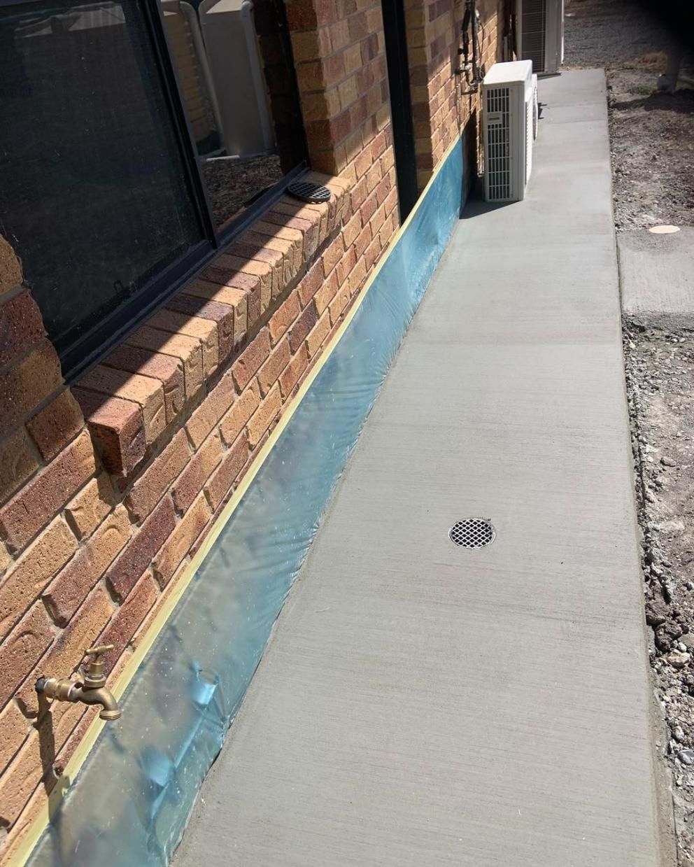 A Sidewalk Is Being Built in Front of A Brick Building — Pedro's Concreting in Toowoomba, QLD
