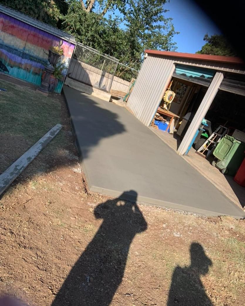 A Shadow of A Person Is Cast on A Concrete Walkway in A Backyard — Pedro's Concreting in Millmerran, QLD