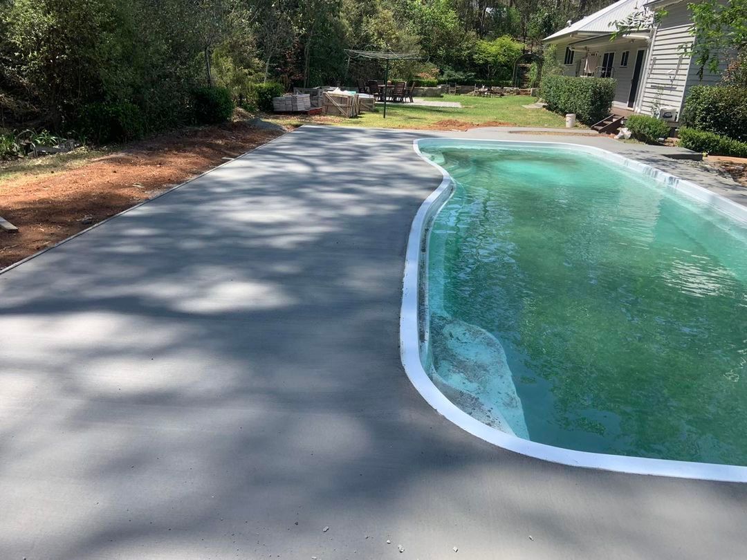 A Large Swimming Pool Is Surrounded by Trees and A Concrete Driveway — Pedro's Concreting in Pittsworth, QLD