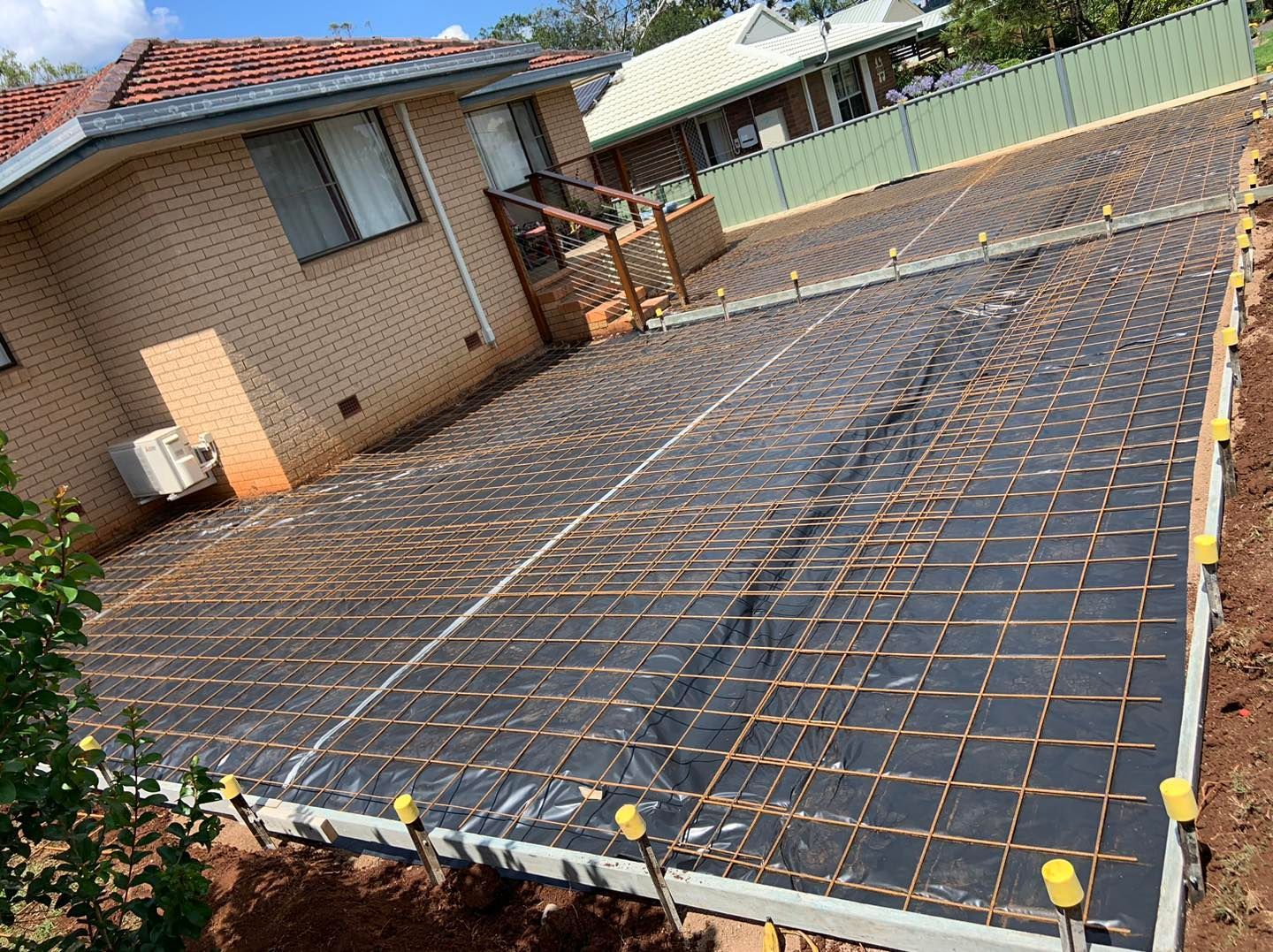 A Concrete Driveway is Being Built in Front of a Brick House — Pedro's Concreting in Pittsworth, QLD