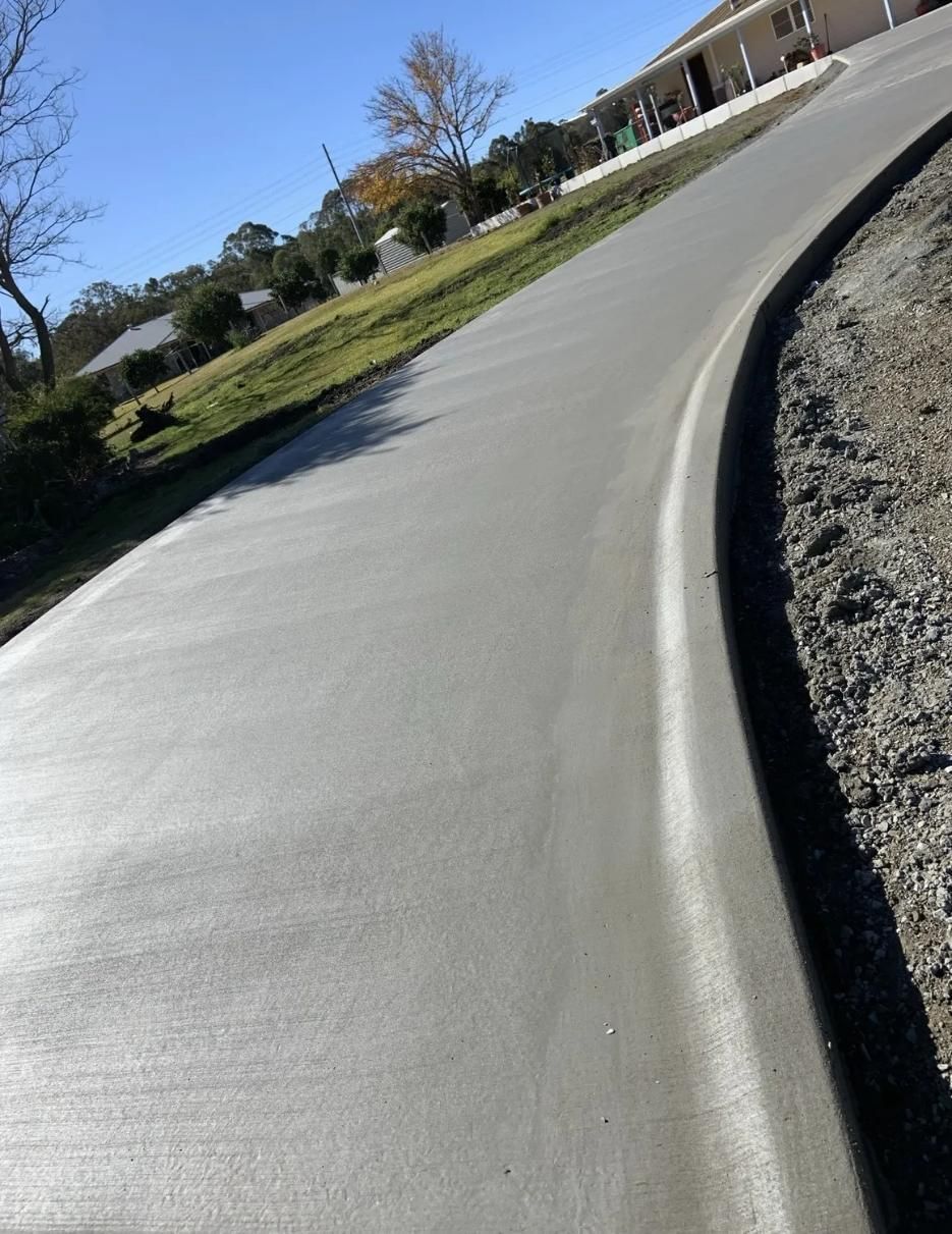 A Curved Concrete Driveway with A House in The Background — Pedro's Concreting in Toowoomba, QLD