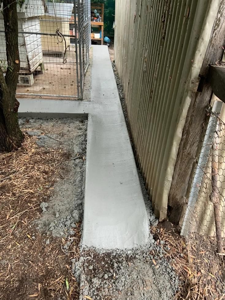 A Concrete Walkway Is Being Built Next to A Chain Link Fence — Pedro's Concreting in Toowoomba, QLD