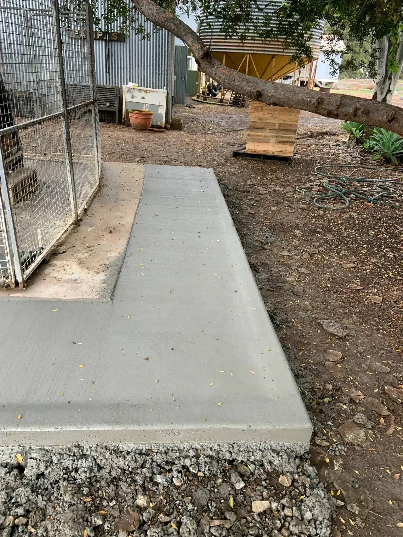 A Concrete Slab Is Sitting in The Middle of A Dirt Field Next to A Fence — Pedro's Concreting in Millmerran, QLD