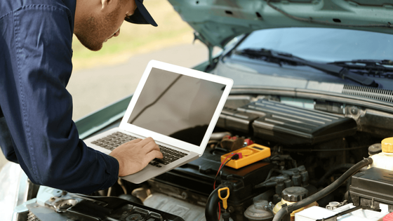 Two mobile mechanics looking under the hood of a car.