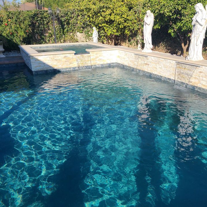 A large swimming pool surrounded by statues and trees.