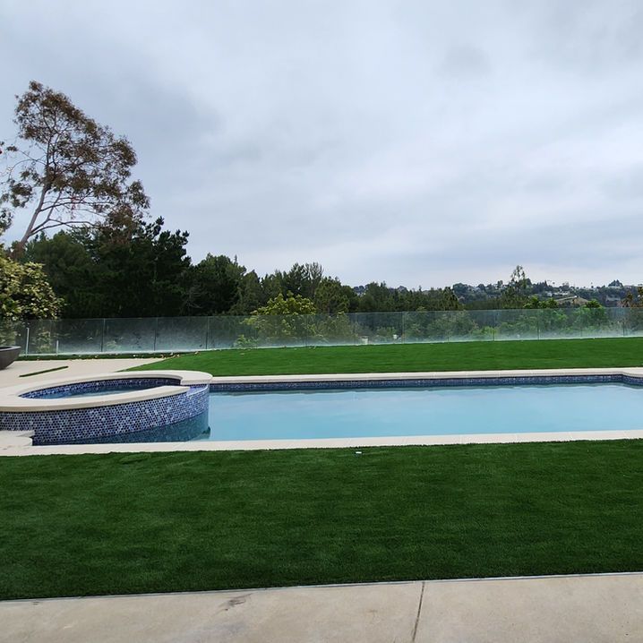 A large swimming pool surrounded by a lush green lawn