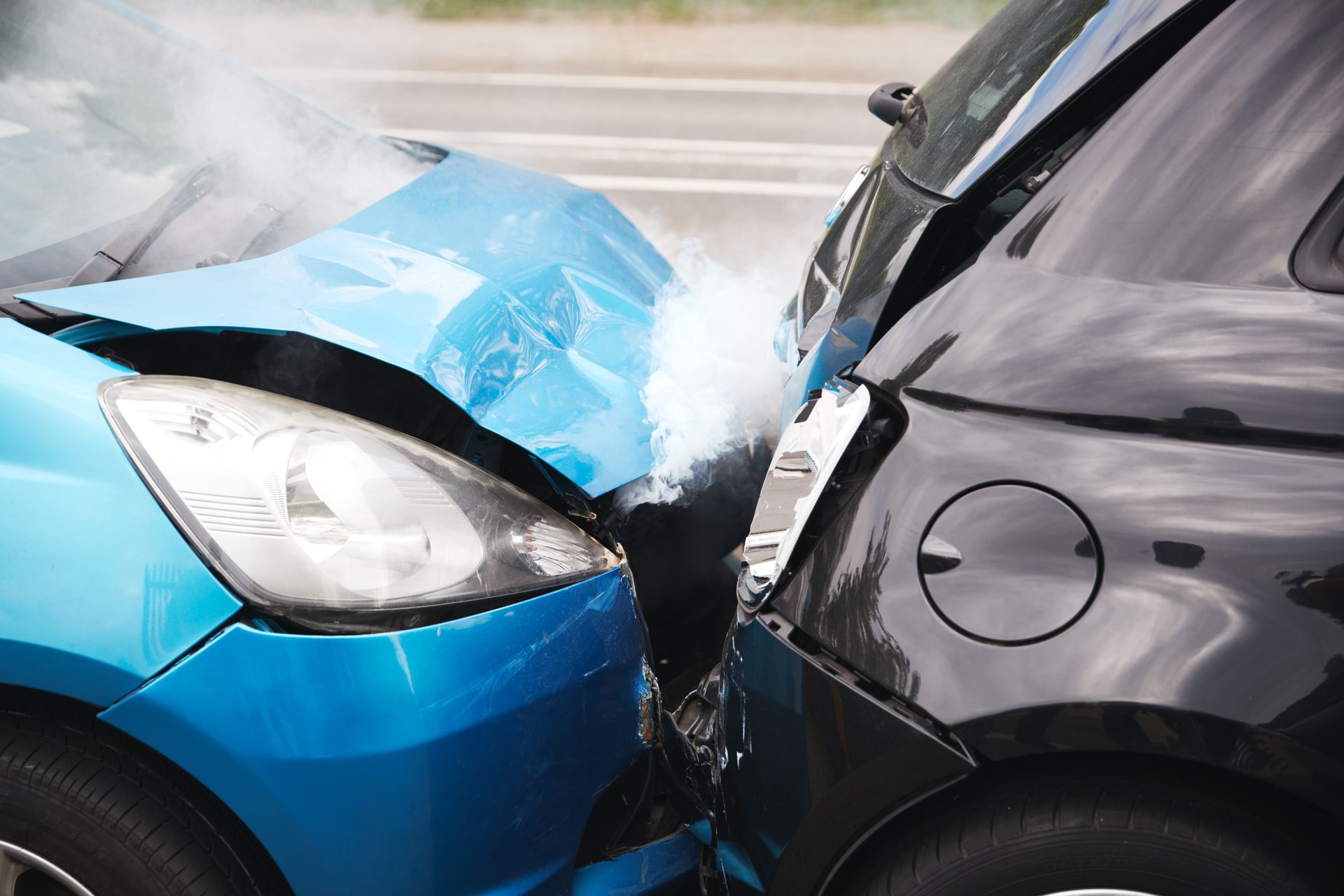 Blue car and black SUV with severe front-end collision on a wet road
