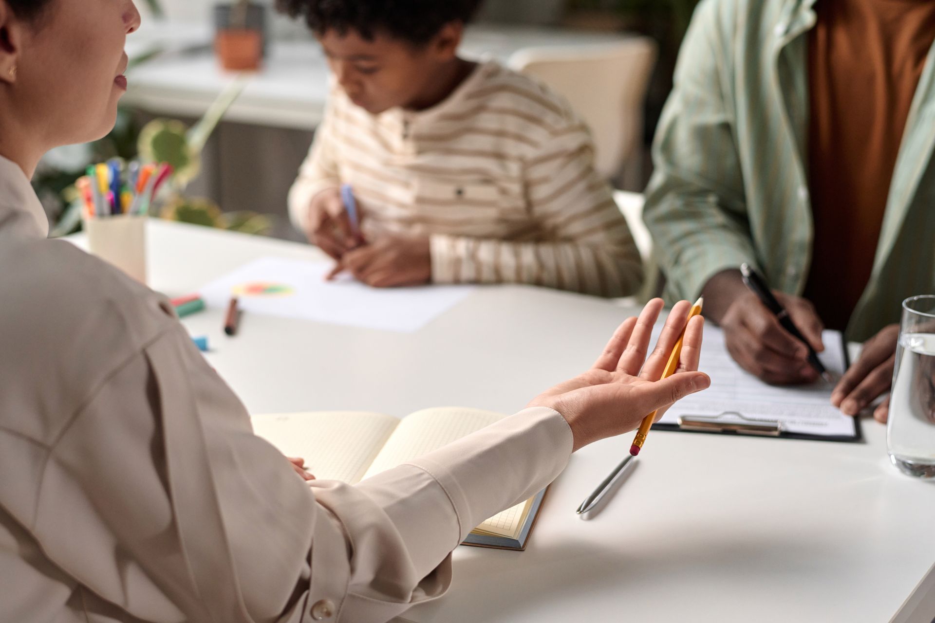 People in a meeting around a white table, one person gesturing while others write notes and draw.